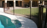 Smoothly curving pool fencing with ball tops on the posts